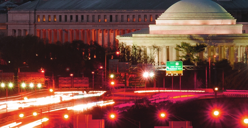 an image of Washington D.C. at night, the traffic lights blurred from long exposure and a government building in the background