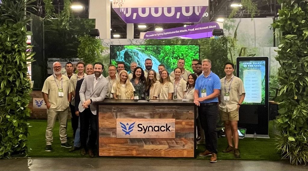 the Synack team gathered around to pose for a photo in the Synack booth at Black Hat