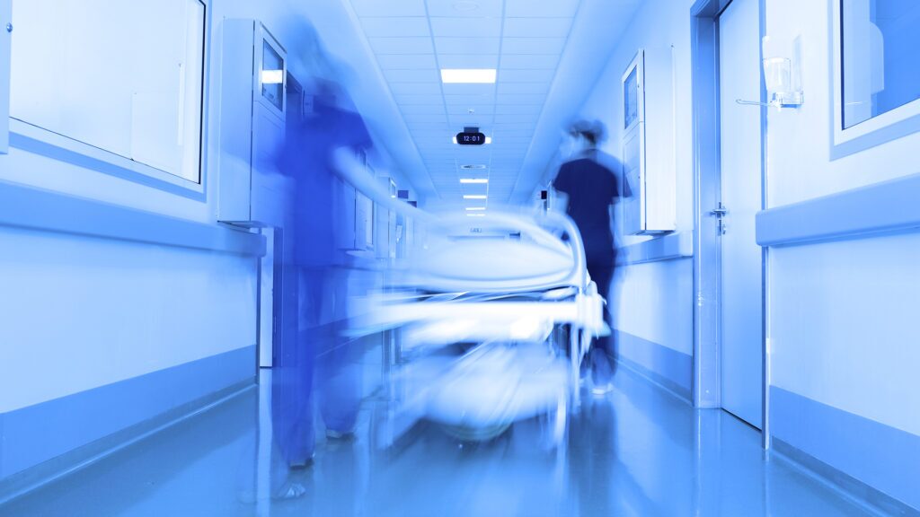 Photo of a medic team running down a hospital hallway with a gurney.