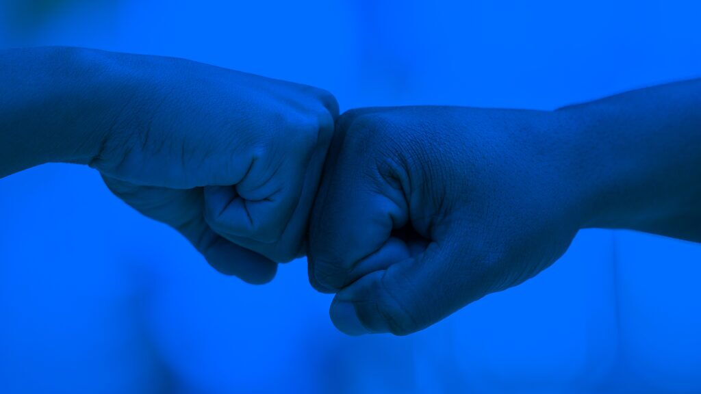 Two fists bumping to symbolize the synergy needed between development and security teams